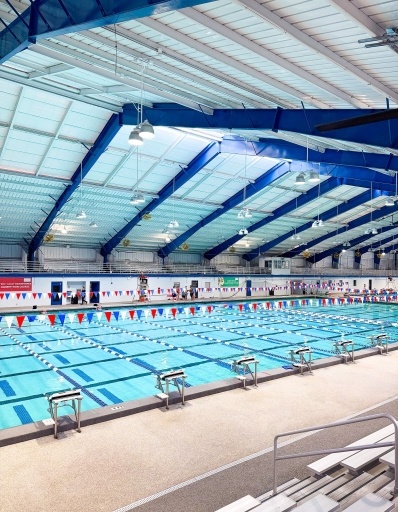 A large indoor pool beneath a tented ceiling with large blue columns. 