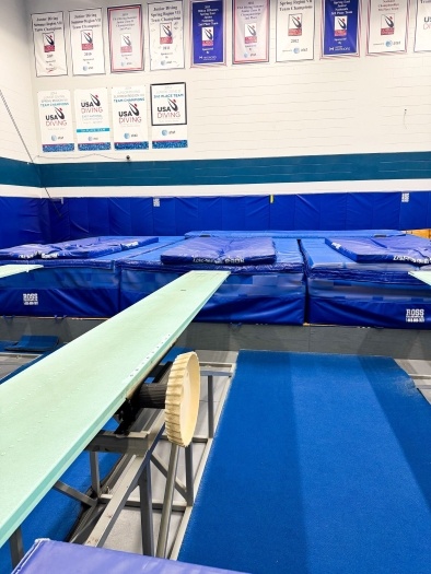 A room with trampolines, gymnastics pads, and other equipment. 