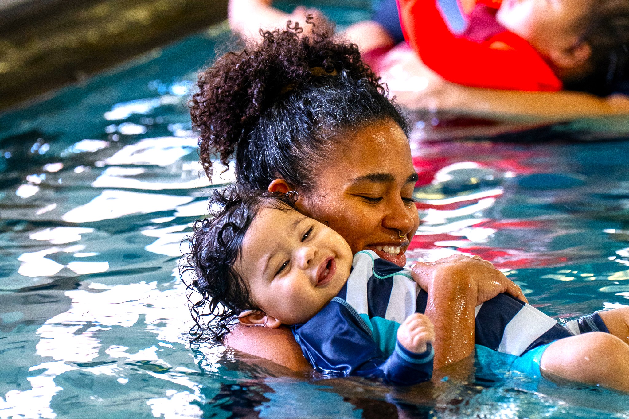 A mom rests her baby on her shoulder in a swim lesson at RAFC. 