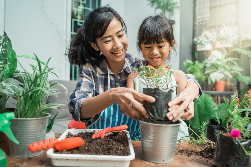 A mom and her daughter pot a plant together in a healthy activity moms and kids can do together. 