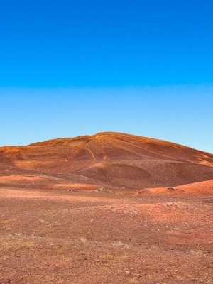 A desolate red landscape with a bright blue sky in the background.