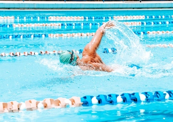A man performing a freestyle swim in a sparkling blue competition swimming pool.