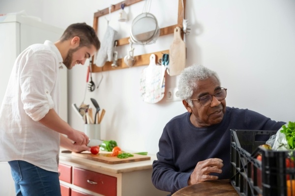 An older man and a younger man cooking a healthy meal together.