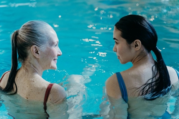 An older woman and a younger woman sitting together in a swimming pool.