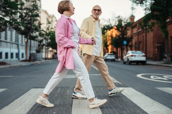 An older couple holding hands while walking down a street.
