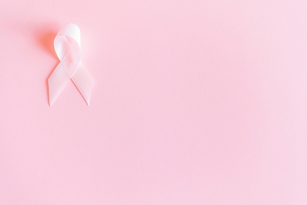 A pink ribbon in front of a plain pink background.