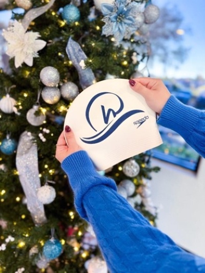 Two hands in front of a Christmas tree holding a sign for Rosen Aquatic and Fitness Center, the perfect place for staying healthy during the holidays.