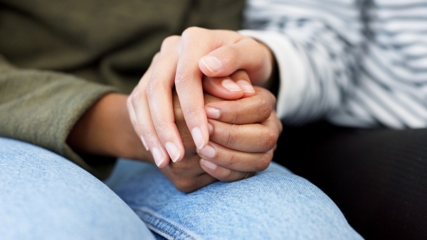 A close-up of two women's hands embracing empathetically. 