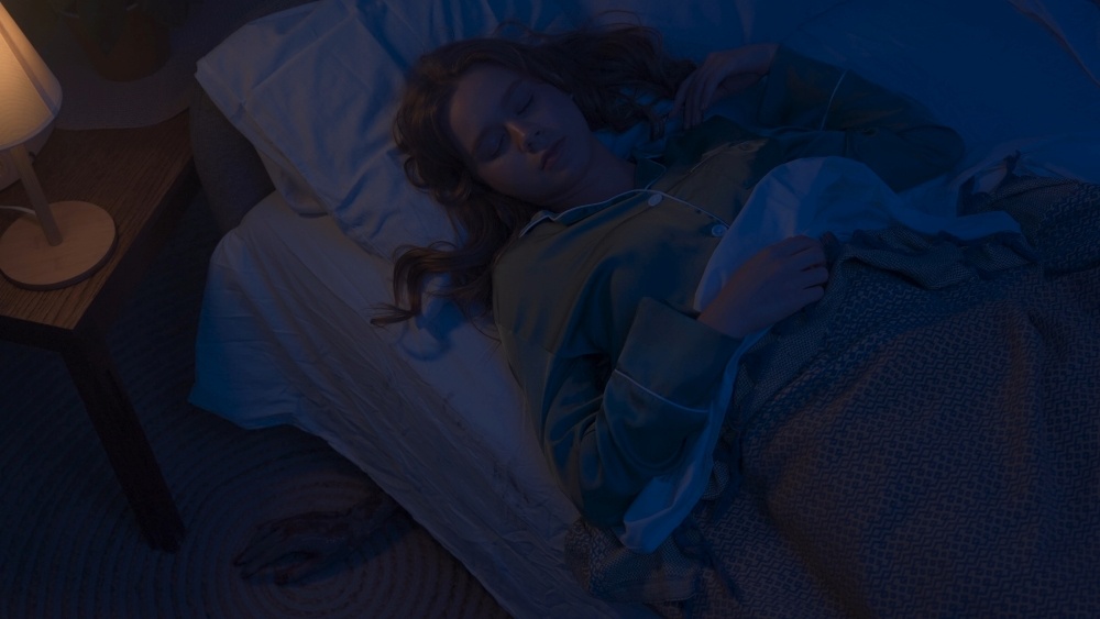 A woman sleeps in a dark room. 