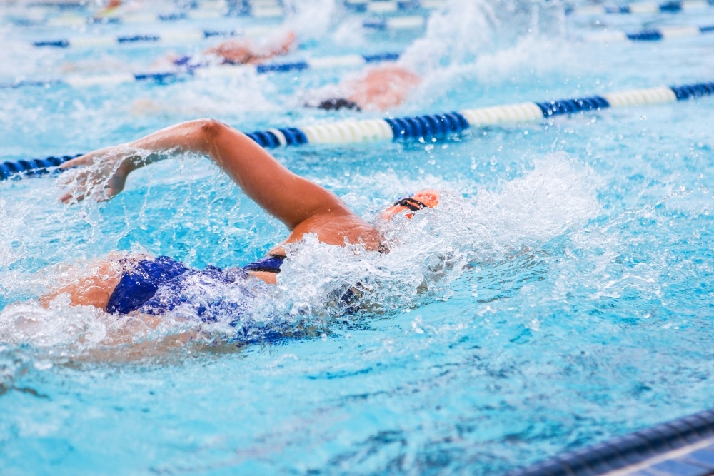 A woman doing the freestyle stroke while lap swimming in a pool.
