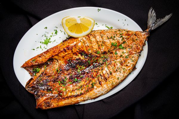 Grilled fish on a white plate, a reliable source of protein for healthy fall foods.