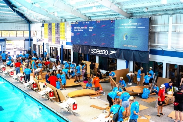 A photo looking down on the pool deck during the RAFC Cardboard Boat Race, where competitors are building boats out of cardboard.